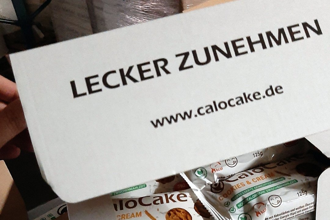 Geöffneter CaloCake Versandkarton im Lager, darin verpackte Riegel